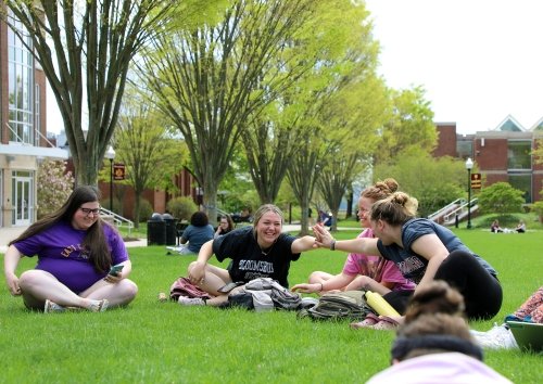 Students celebrate a correct answer during an class held outside on the Academic Quad